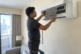 فني يفحص فلتر مكيف مثبت على الحائط