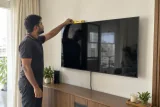 فني يفحص استواء تلفزيون مثبت على الحائط