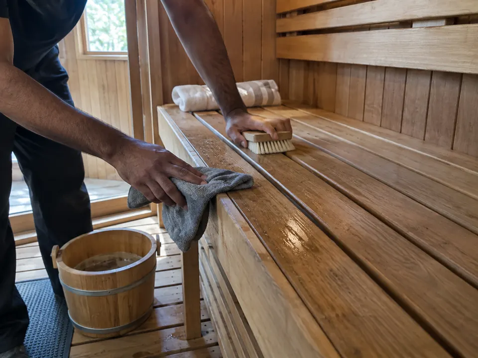 Cleaning wooden sauna benches with a cloth and soft brush